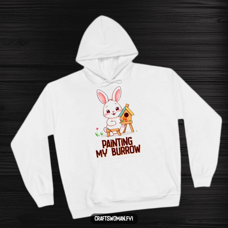 Funny rabbit painting a birdhouse with vibrant colors on a cozy hoodie, perfect for artists and nature lovers.